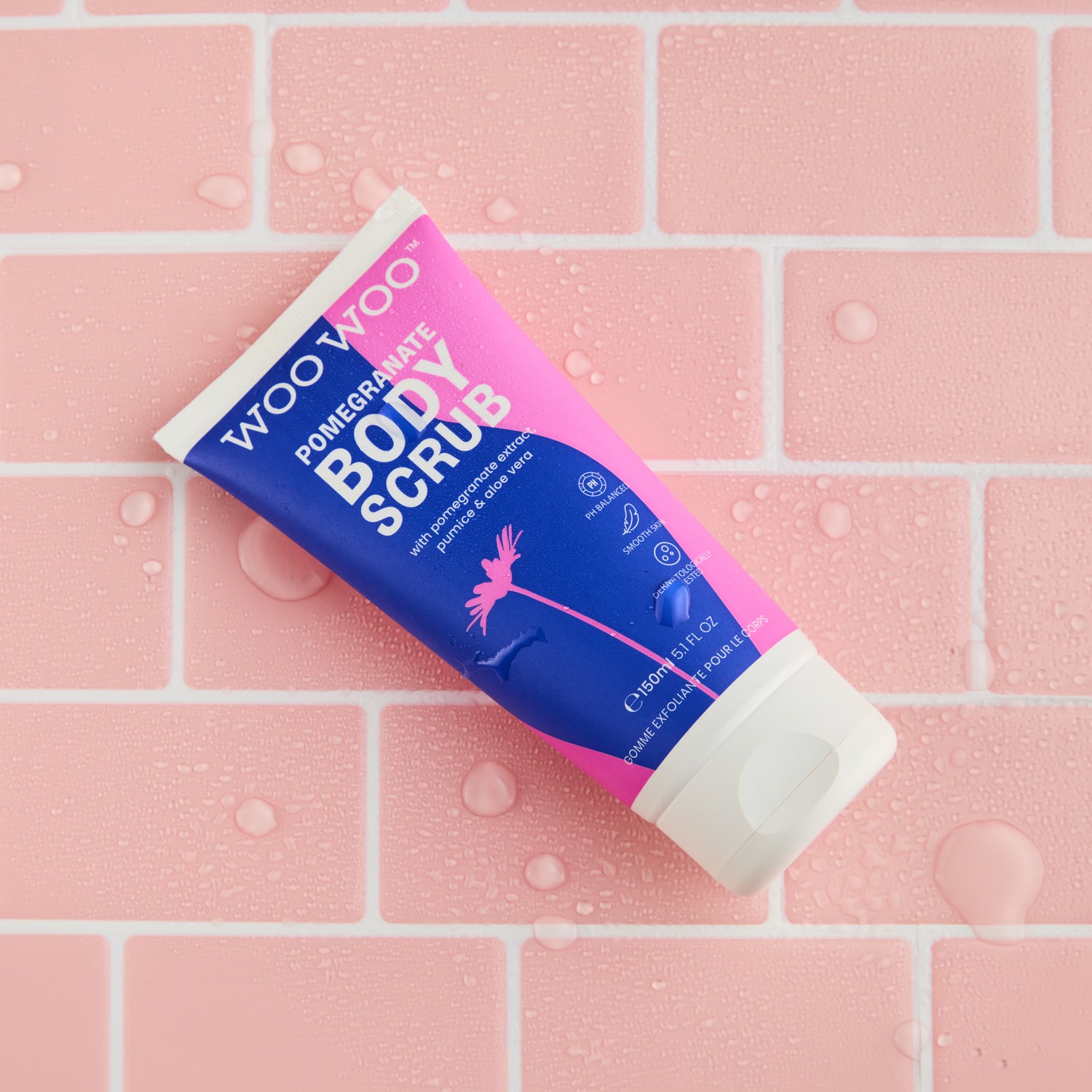 Tube of body scrub on a pink tiled background