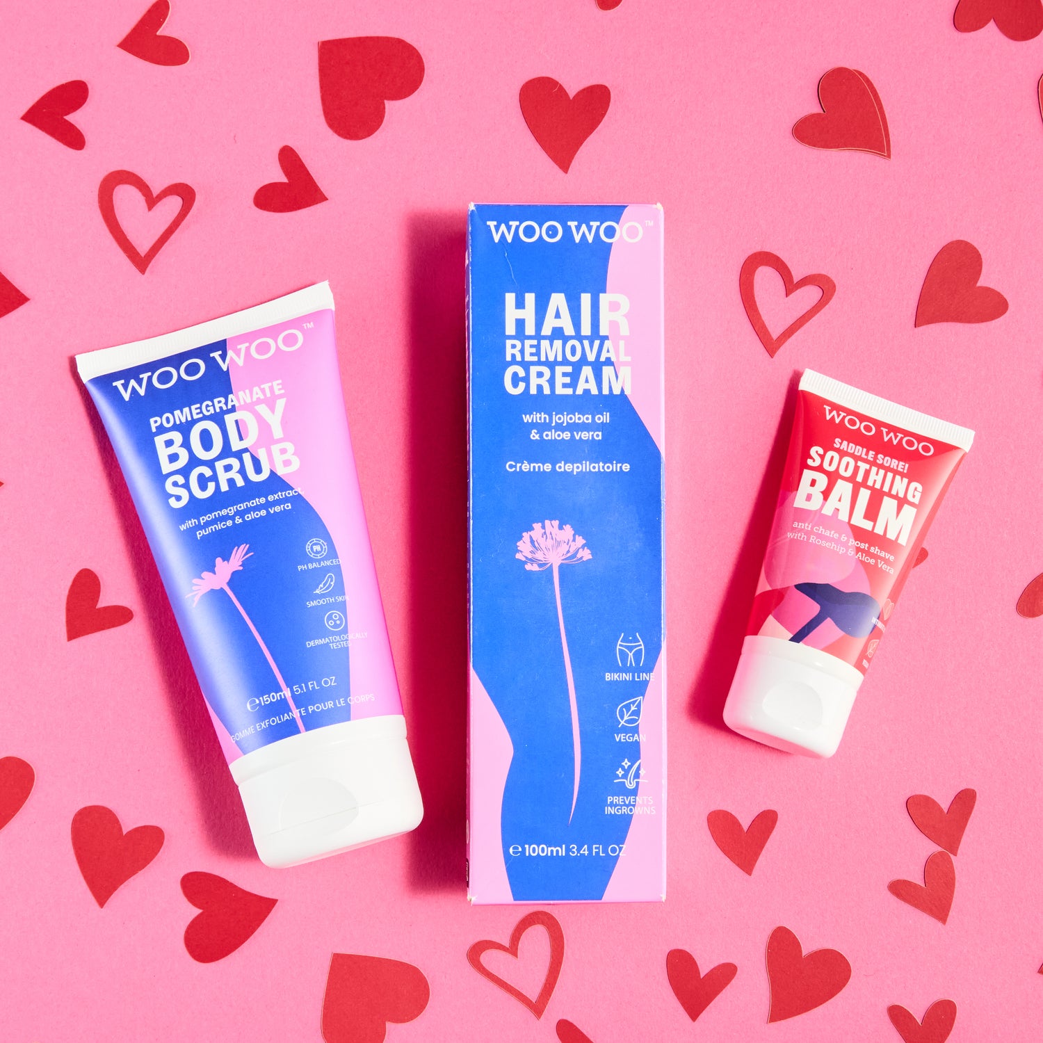 Three skincare products on a pink background with red heart shapes